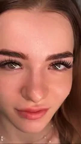 Video Concept: Using the uploaded image of the girl with long, full eyelashes, create a short, cinematic animation with a tiny, fluffy, Seussian-inspired green creature.